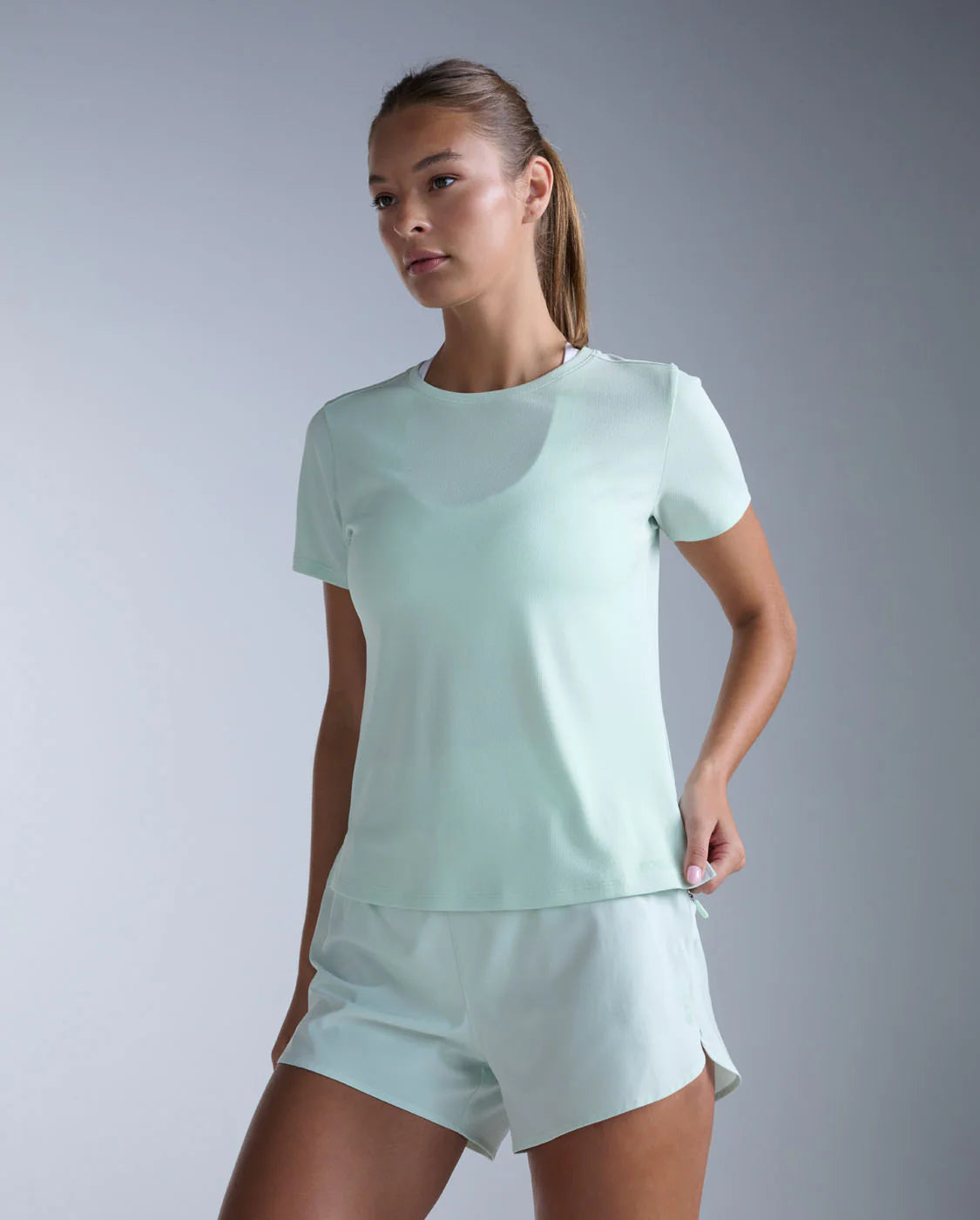Woman wearing a light green athletic outfit on a gray background