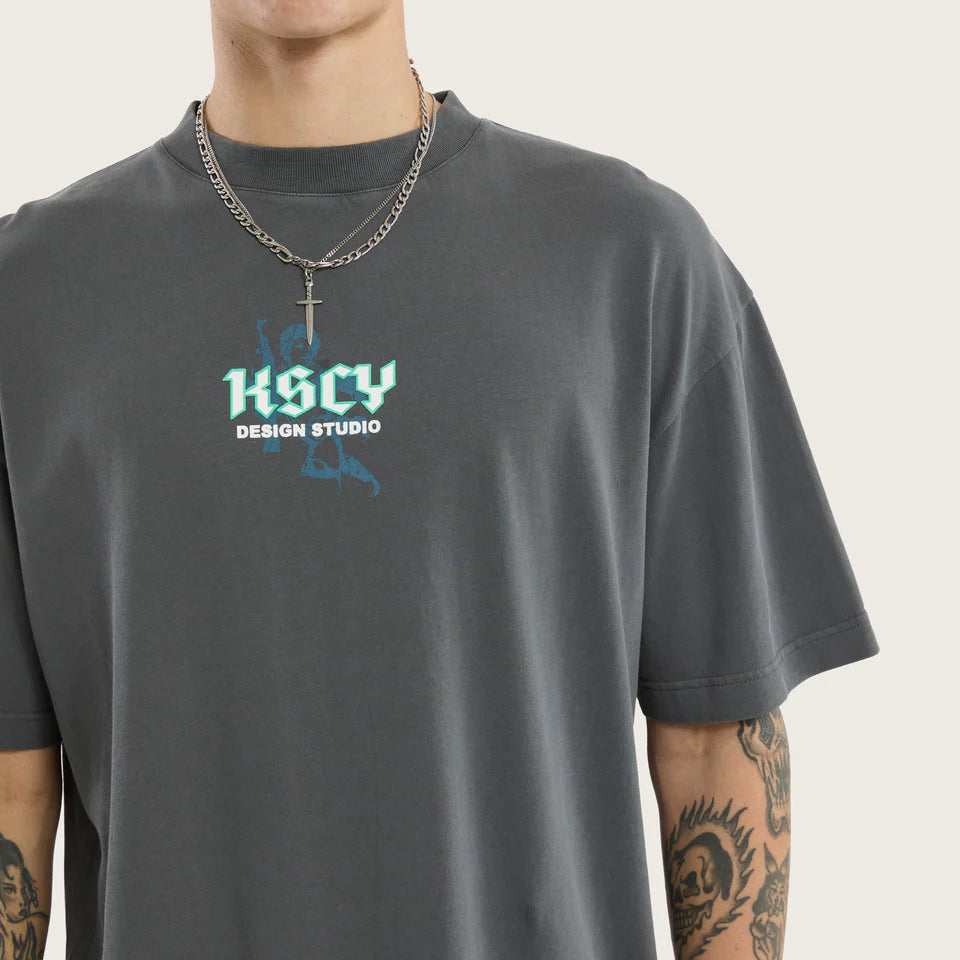 Person wearing a dark gray t-shirt with 'KSCY Design Studio' logo on a light gray background