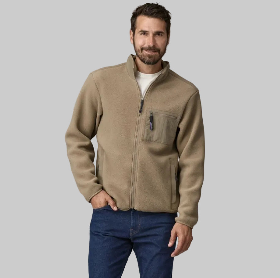 A man wearing a beige full-zip fleece jacket with a chest pocket, standing against a white background.