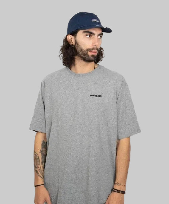 A man wearing a gray Patagonia crew neck t-shirt with a small logo on the chest, paired with a blue baseball cap.