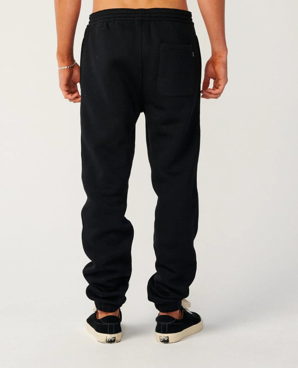 Person wearing black sweatpants on a plain background