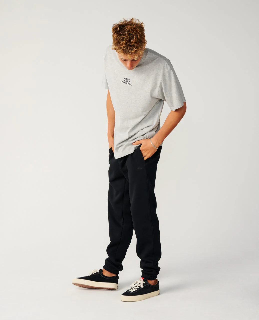 Person wearing a gray t-shirt and black pants on a white background