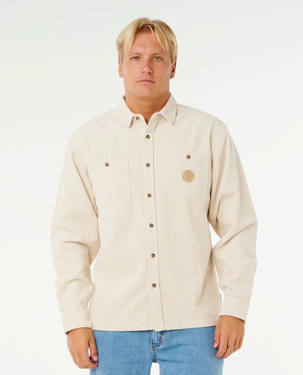 Man wearing a cream-colored button-up shirt with a logo on a white background