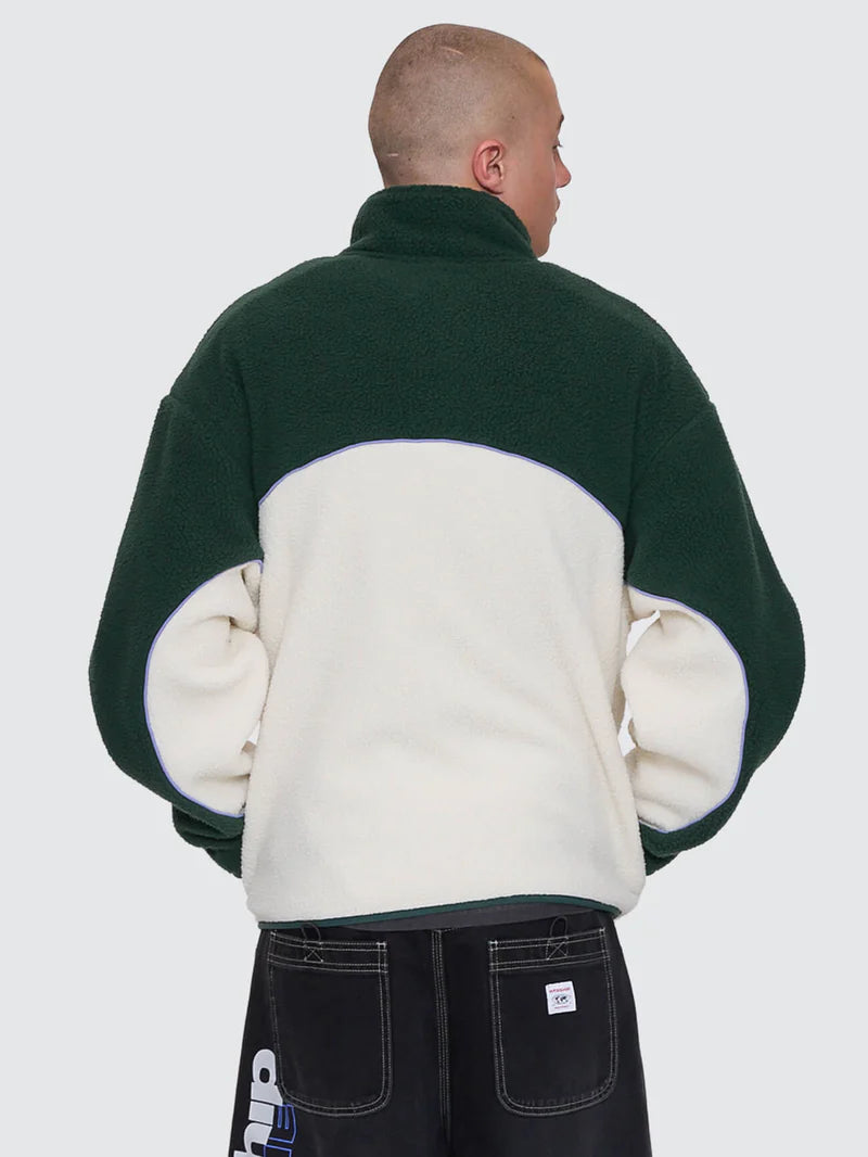Person wearing a green and white fleece jacket on a plain background