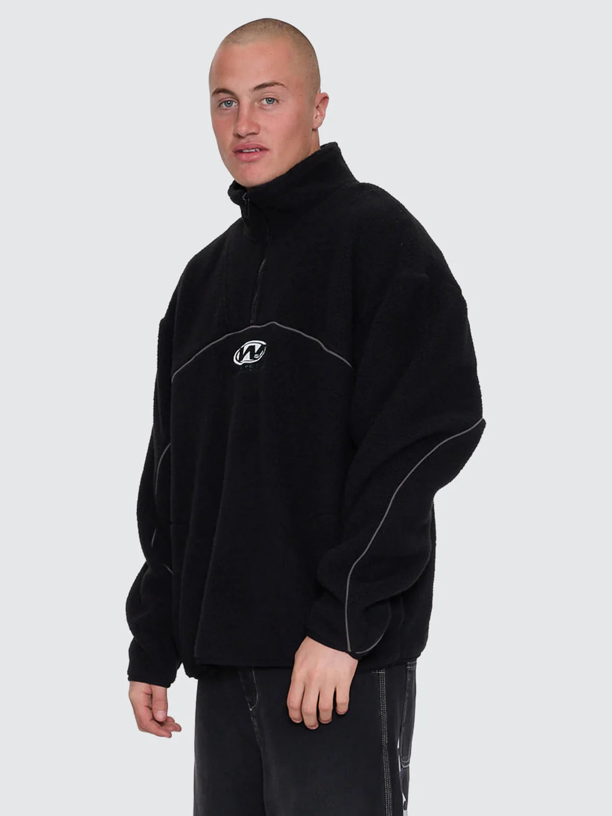 Person wearing a black fleece pullover with a logo on a white background