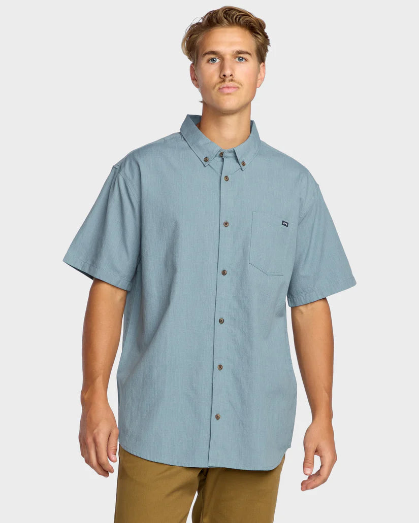 Man wearing a light blue short-sleeve shirt on a white background
