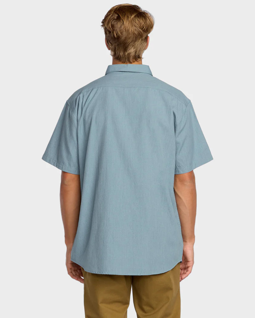 Person wearing a light blue short-sleeve shirt on a white background