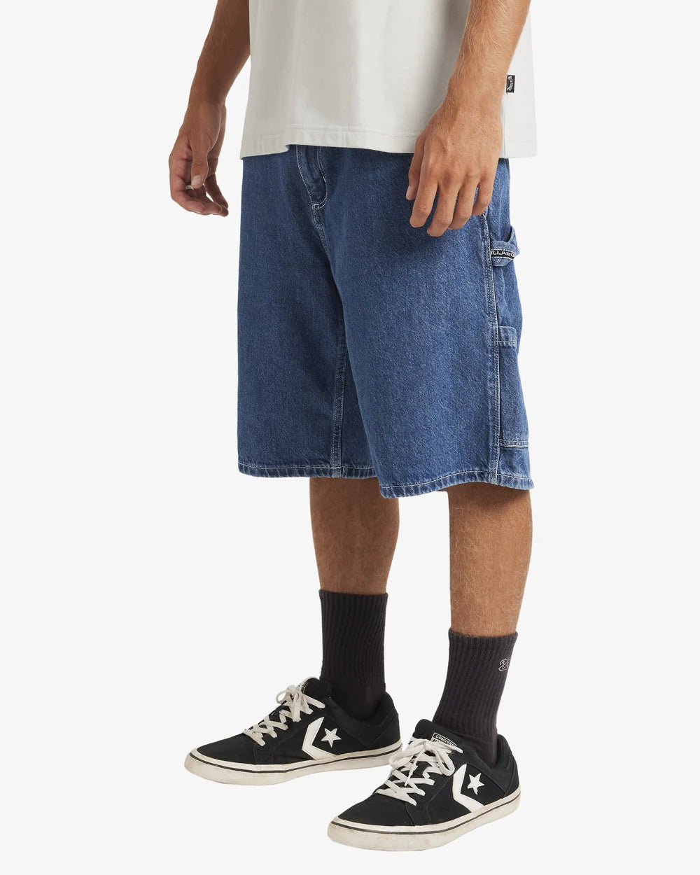 Person wearing blue denim shorts, black sneakers, and dark socks on a white background