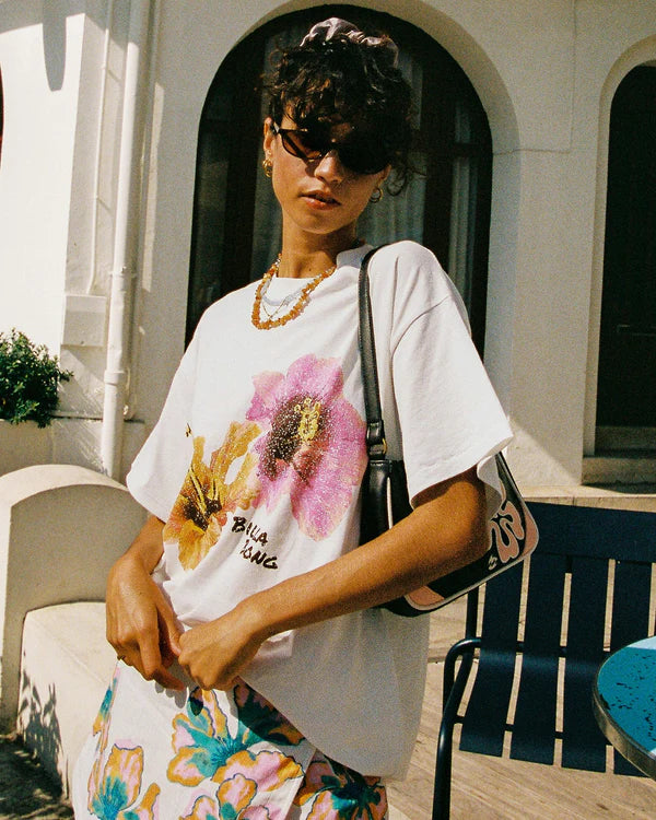 Person wearing a white t-shirt with floral design outdoors