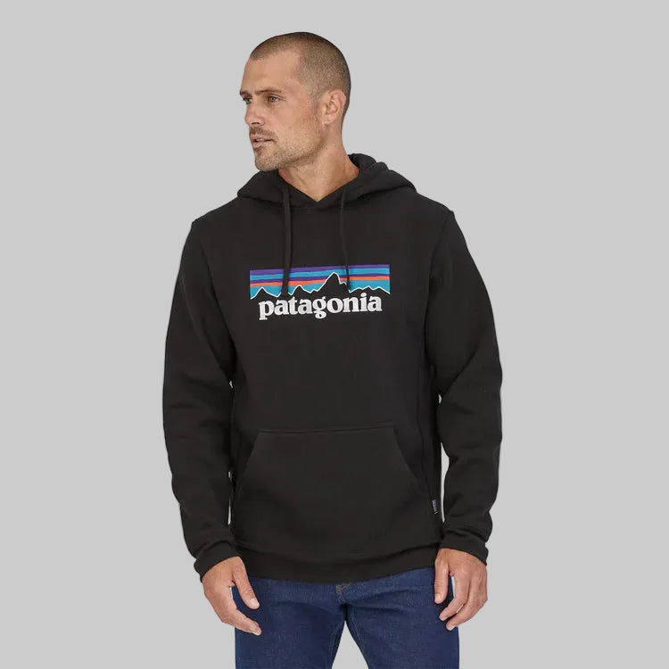 A man wearing a black hoody sweatshirt with the Patagonia logo and a colorful geometric pattern on the front.