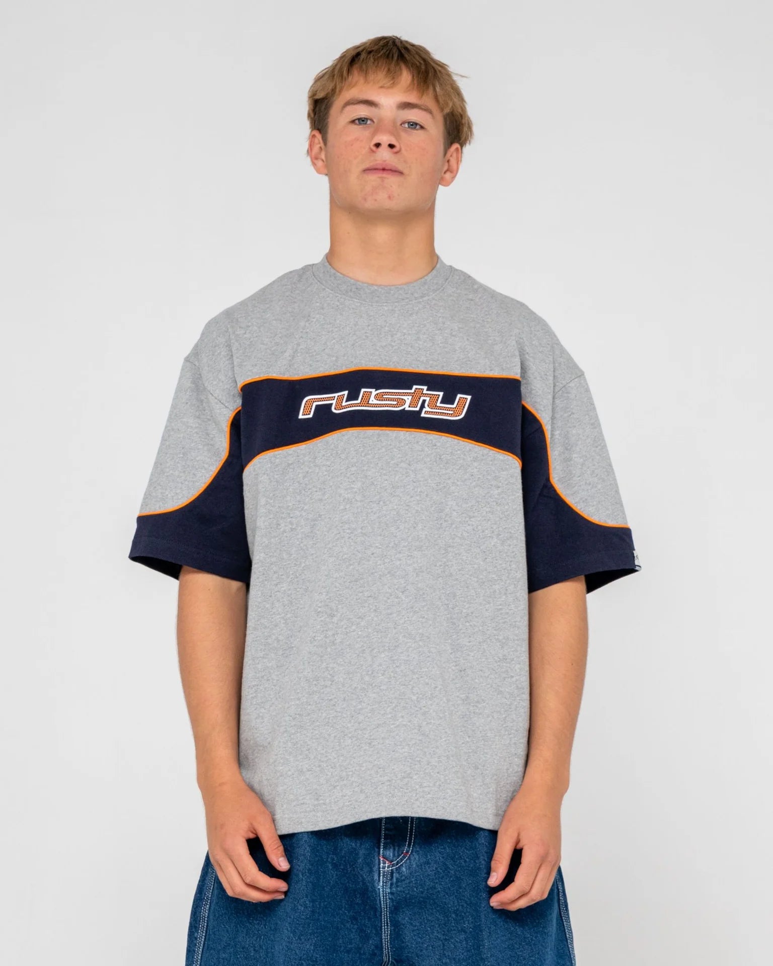 Person wearing a gray and navy oversized t-shirt with 'Rusty' branding on a white background