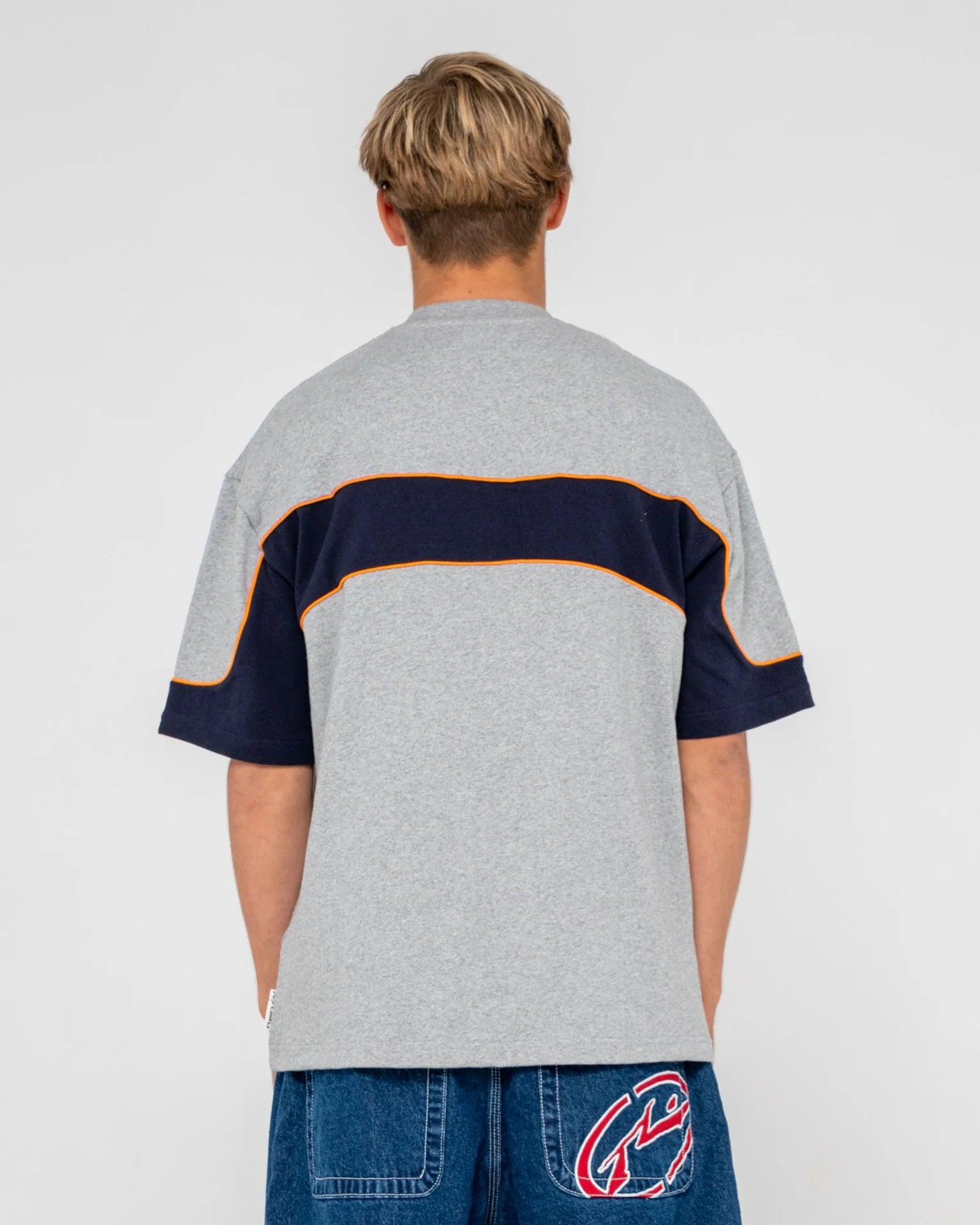 Person wearing a gray and navy color-blocked shirt on a plain background