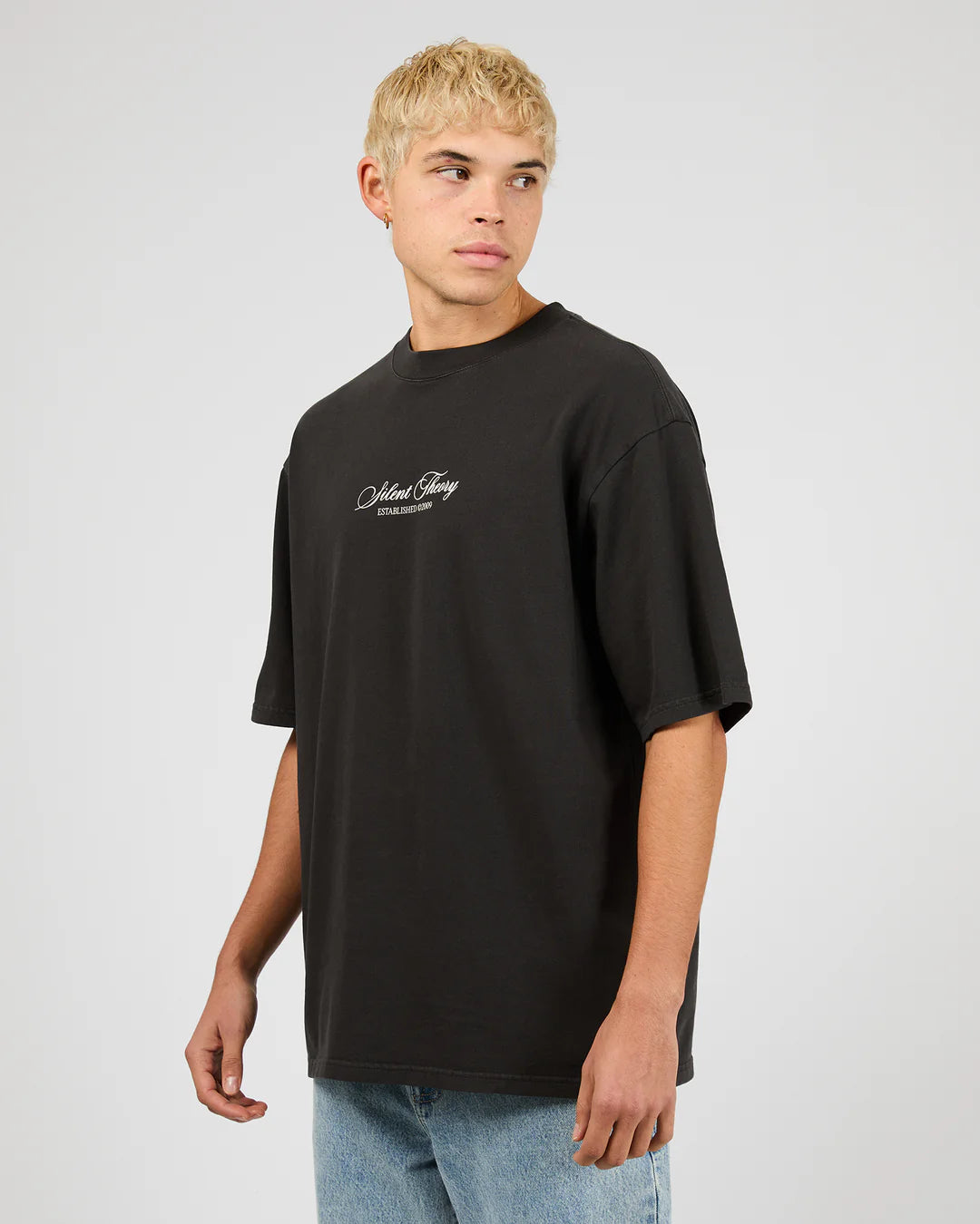 Person wearing a black t-shirt with a logo on a plain background