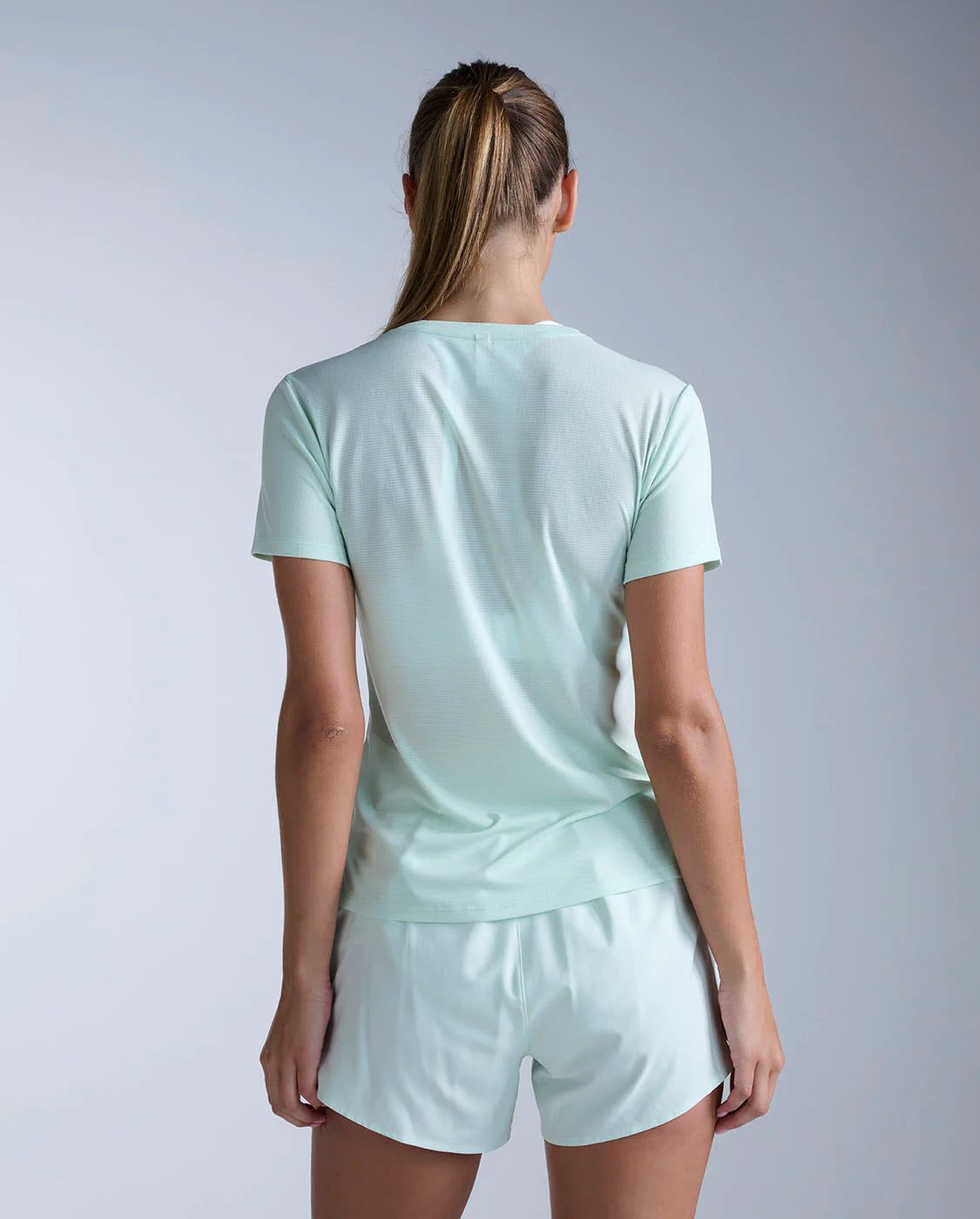 Person wearing a light green t-shirt and shorts set on a plain background