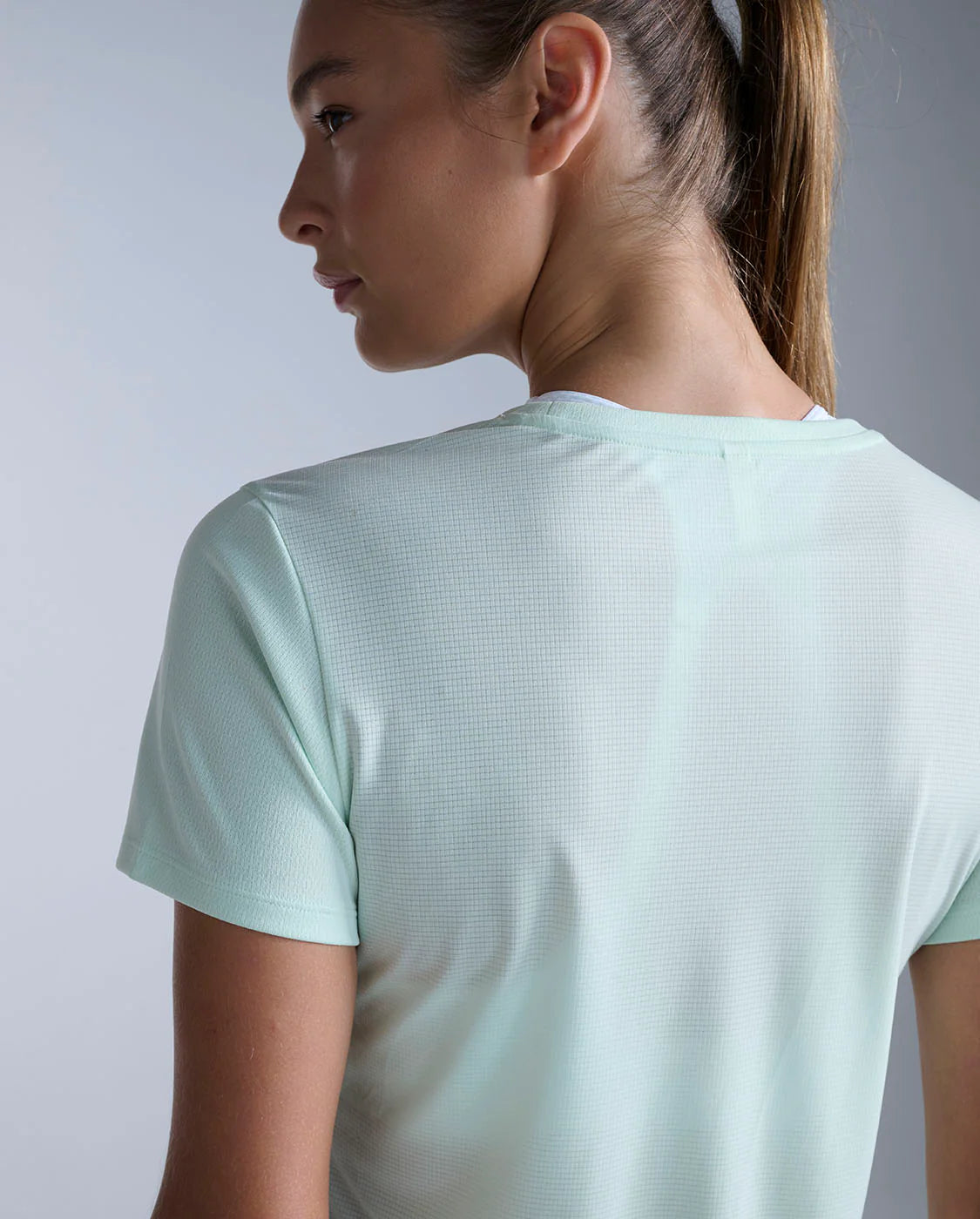Woman wearing a light green athletic shirt against a plain background