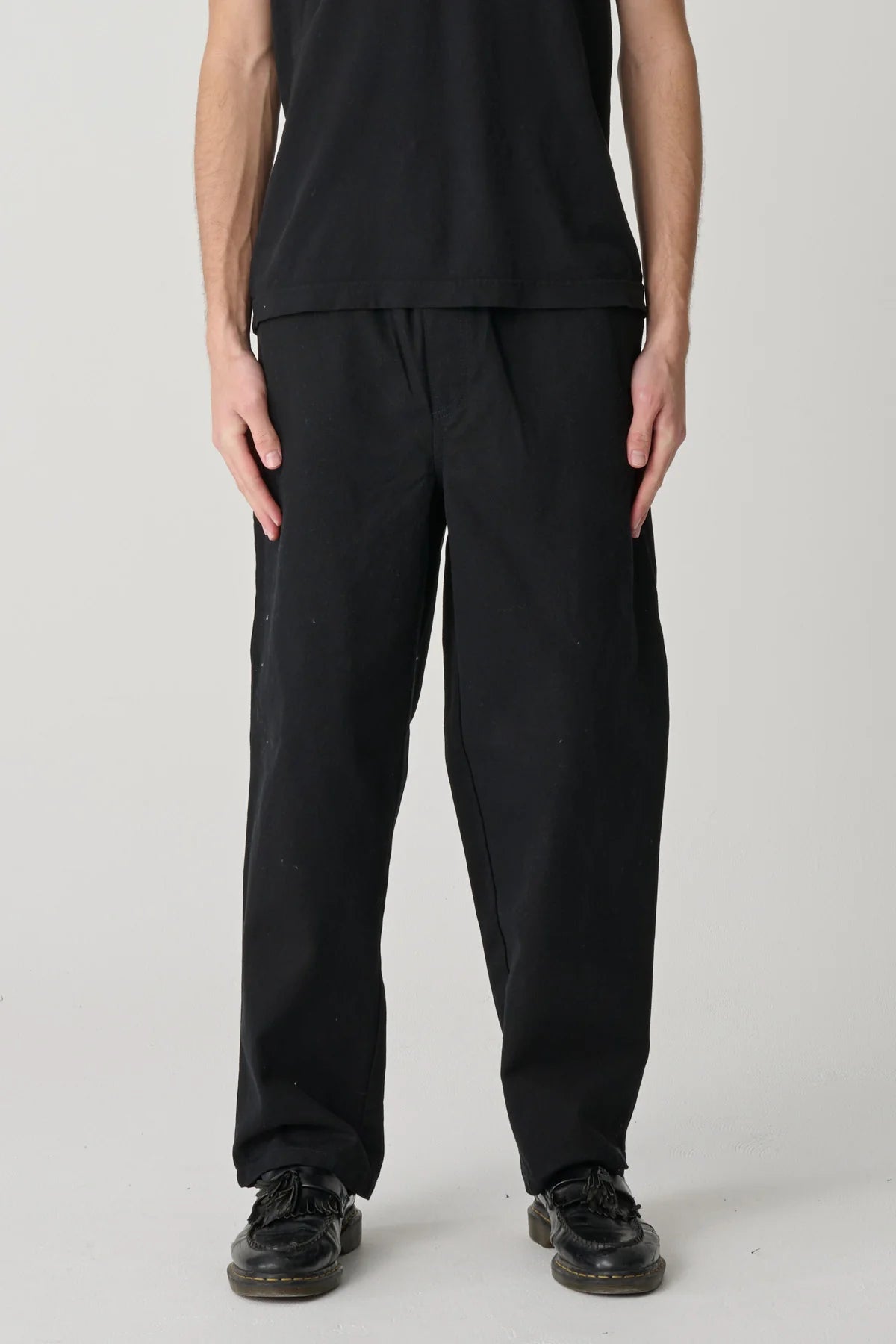 Person wearing black pants and a black top on a plain background
