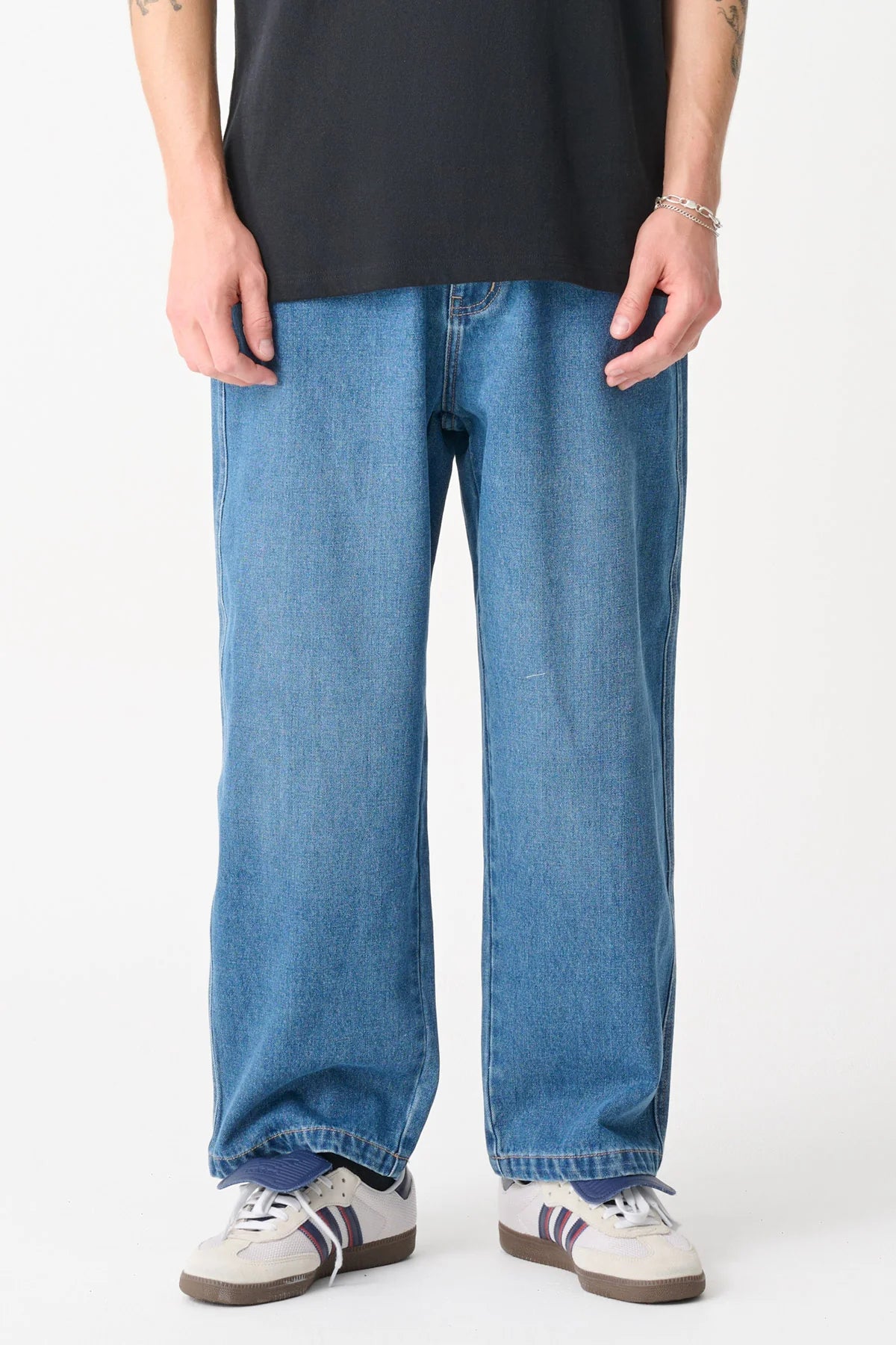 Person wearing blue jeans and a black shirt on a white background