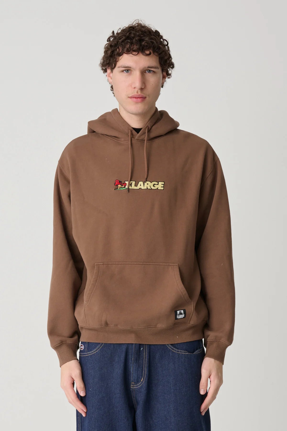 Person wearing a brown hoodie with an XLarge logo on a plain background