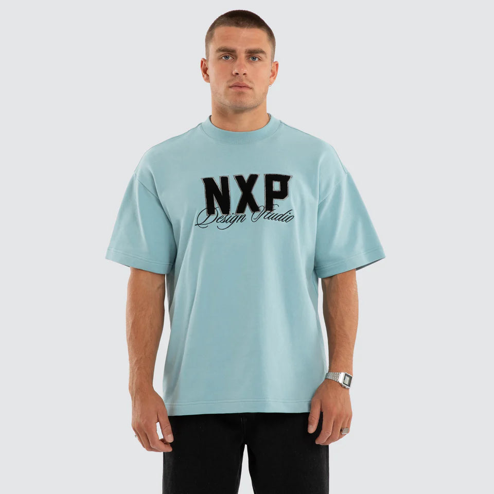 Man wearing a light blue t-shirt with 'NXP' logo on a white background