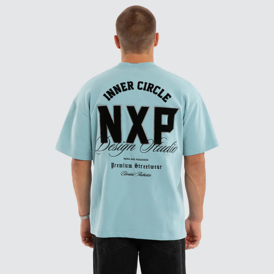 Person wearing a light blue t-shirt with 'INNER CIRCLE NXP Design Studio' text on the back.