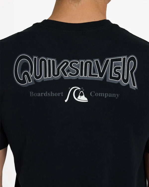 Close-up back view of a person wearing a black Quiksilver t-shirt with a large white and gray outlined Quiksilver logo and 'Boardshort Company' text on the back.