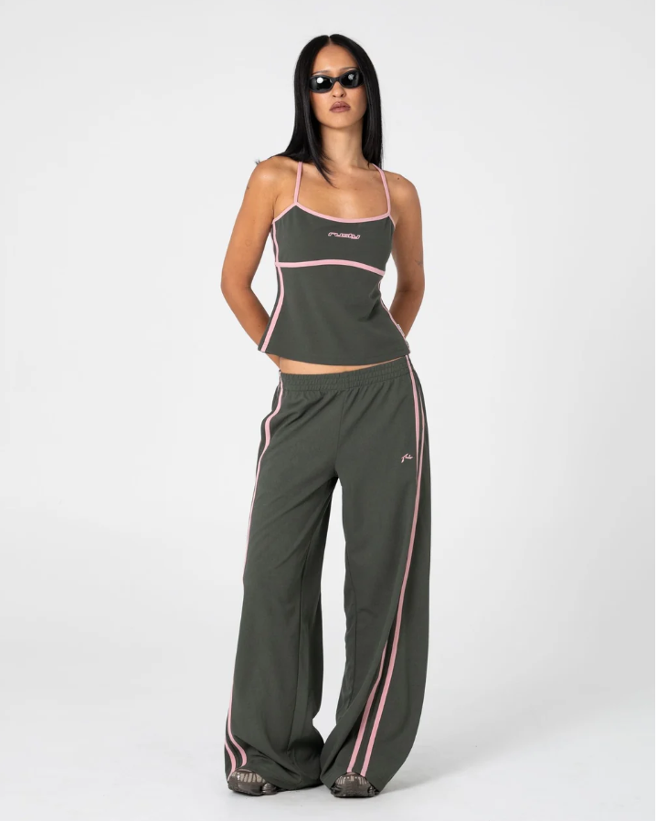 A person shown from the back wearing loose, wide-leg sweatpants in an olive green color, paired with a matching dark top, against a plain white studio background. SISTER BRONSON LOW RISE WIDE LEG PANT SPB GREEN PINK WIDE LEG TRACKPANT LADIES RUSTY