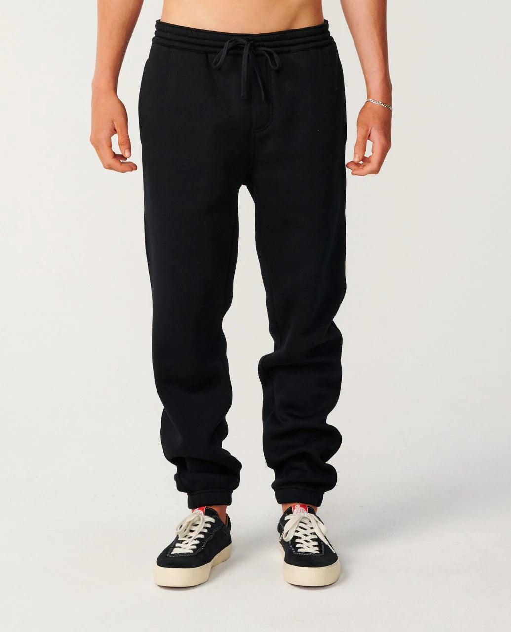 Person wearing black sweatpants on a plain background