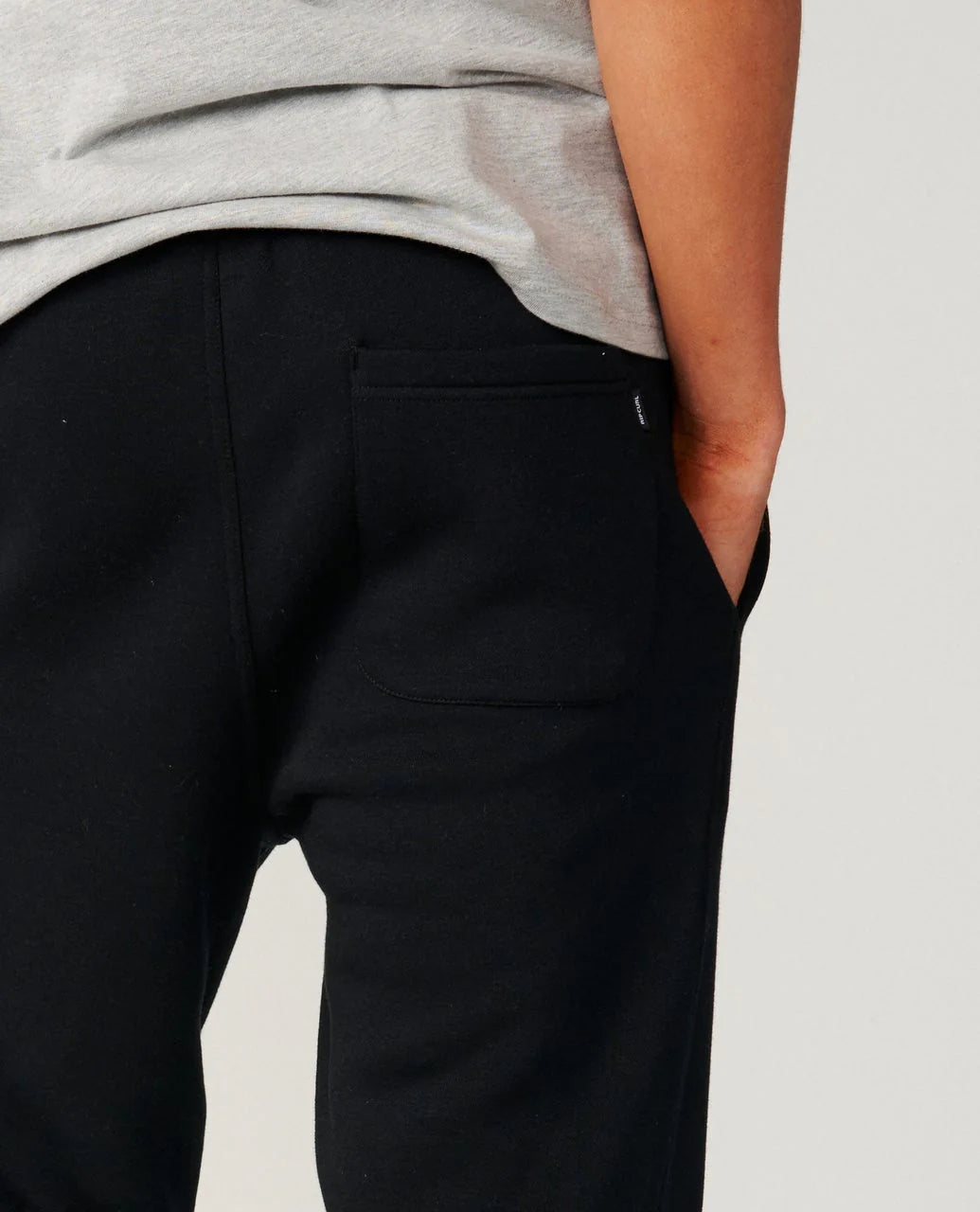 Person wearing black pants with a gray shirt on a light gray background