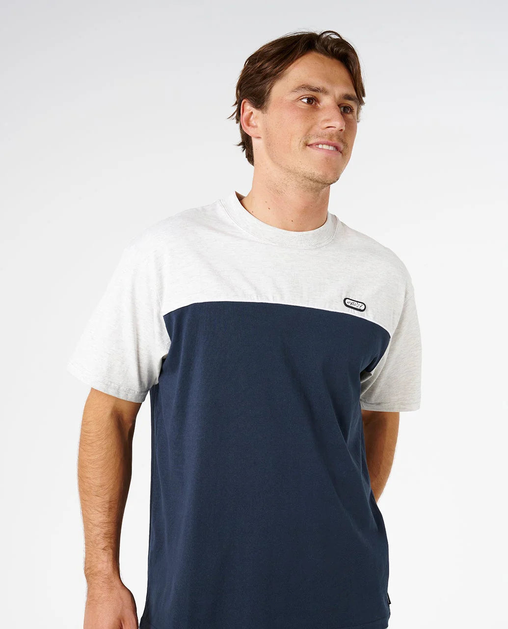 Man wearing a white and navy color-blocked t-shirt on a plain background