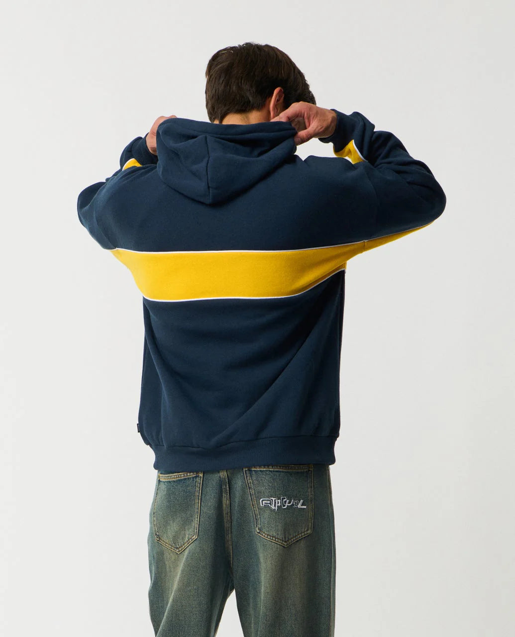 Person wearing a navy and yellow hoodie with a plain background