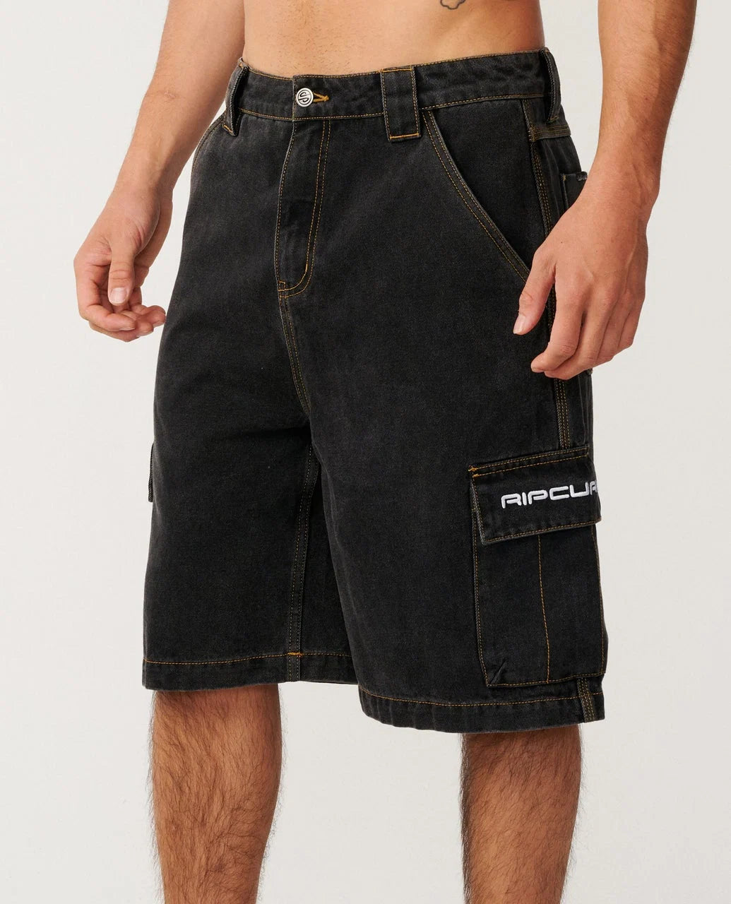 A person wearing black Rip Curl cargo shorts with a white logo on the side pocket, shown from the waist to mid-thigh against a plain light background.