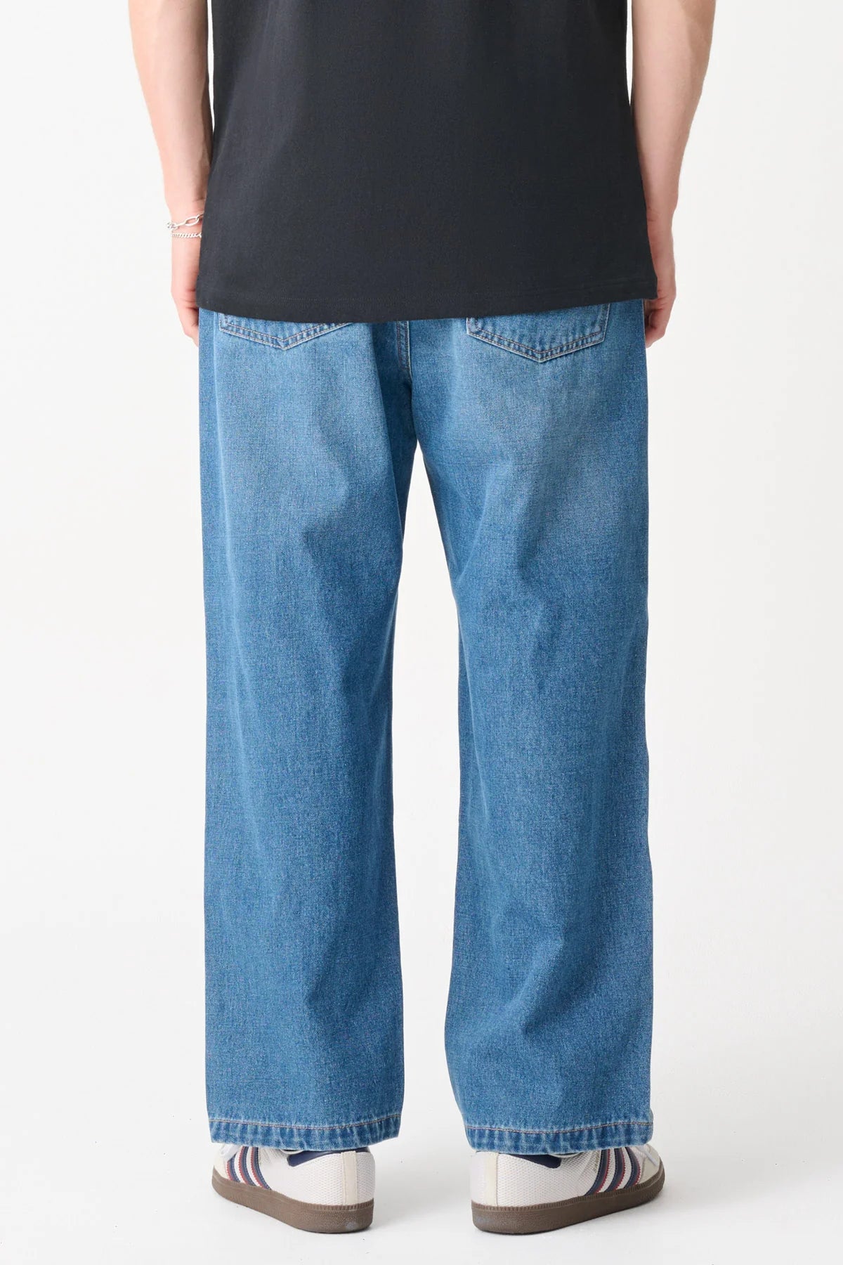Person wearing blue jeans and a black shirt on a white background