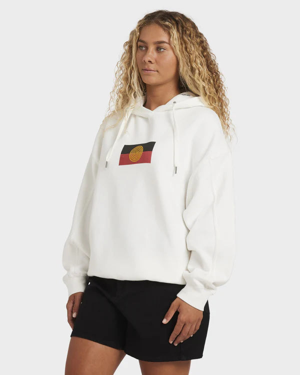 Person wearing a white hoodie with a flag design on a plain background