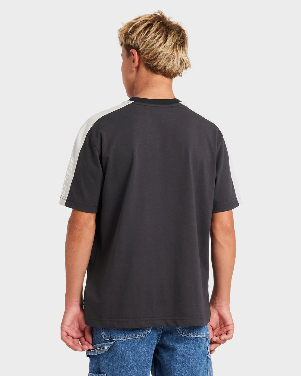 Person wearing a black t-shirt with a white stripe on the back, standing against a plain background