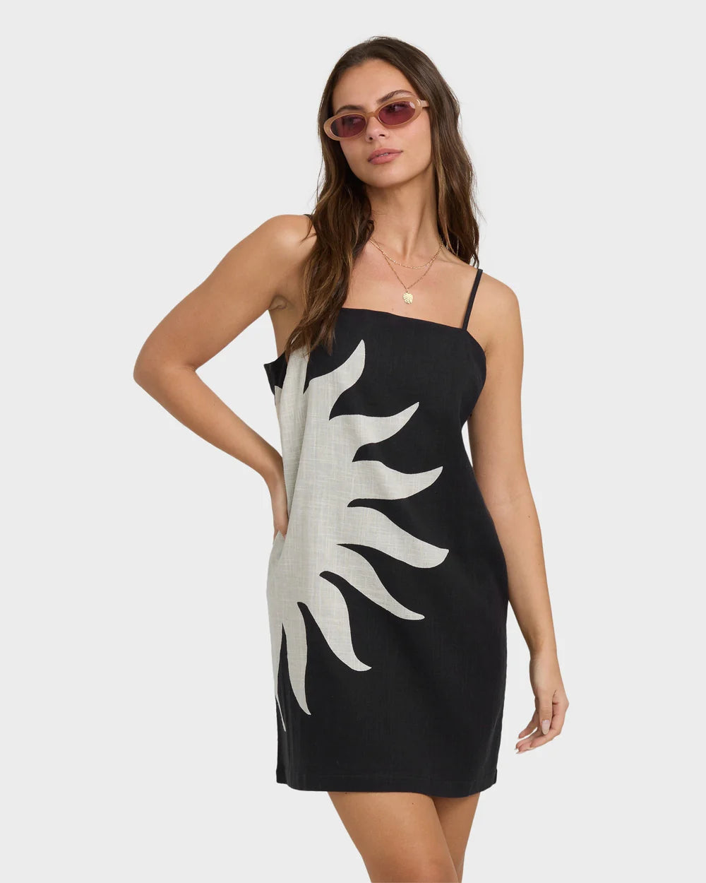 Woman wearing a black dress with a white abstract design on a plain background
