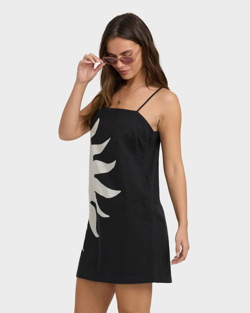 Woman wearing a black slip dress with a white design on a plain background