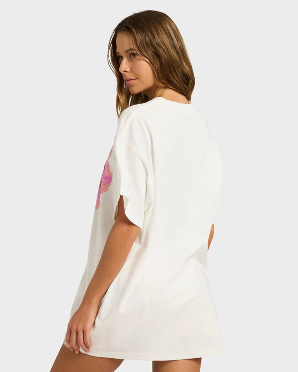 Woman wearing a white dress with a colorful design on a plain background