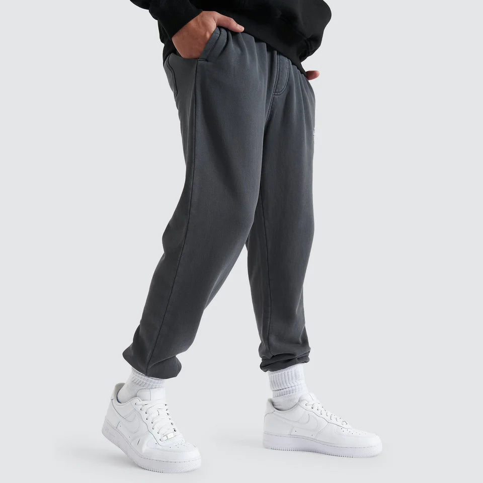 Person wearing gray sweatpants and white sneakers on a light gray background