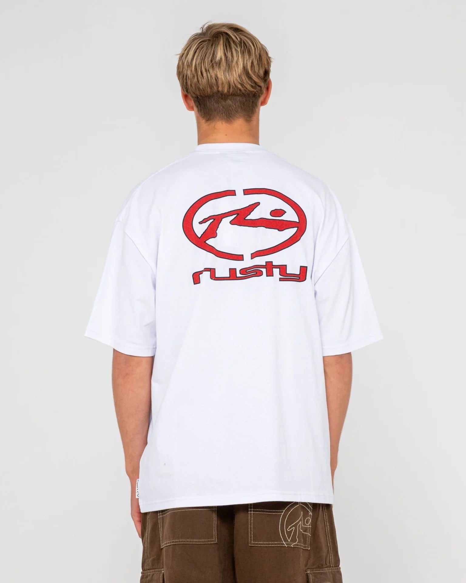 Person wearing a white t-shirt with a red logo on the back against a plain background