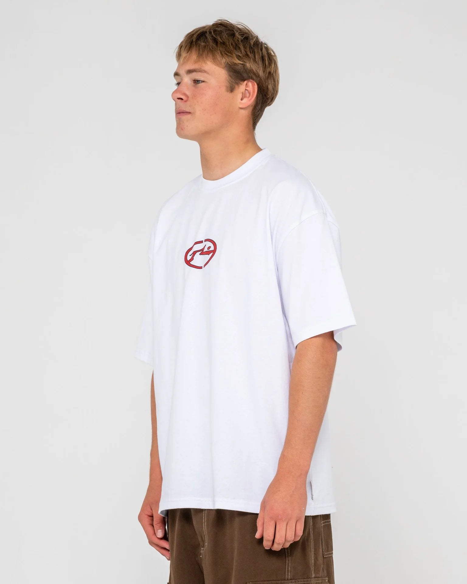 Person wearing a white t-shirt with a red logo on a plain background