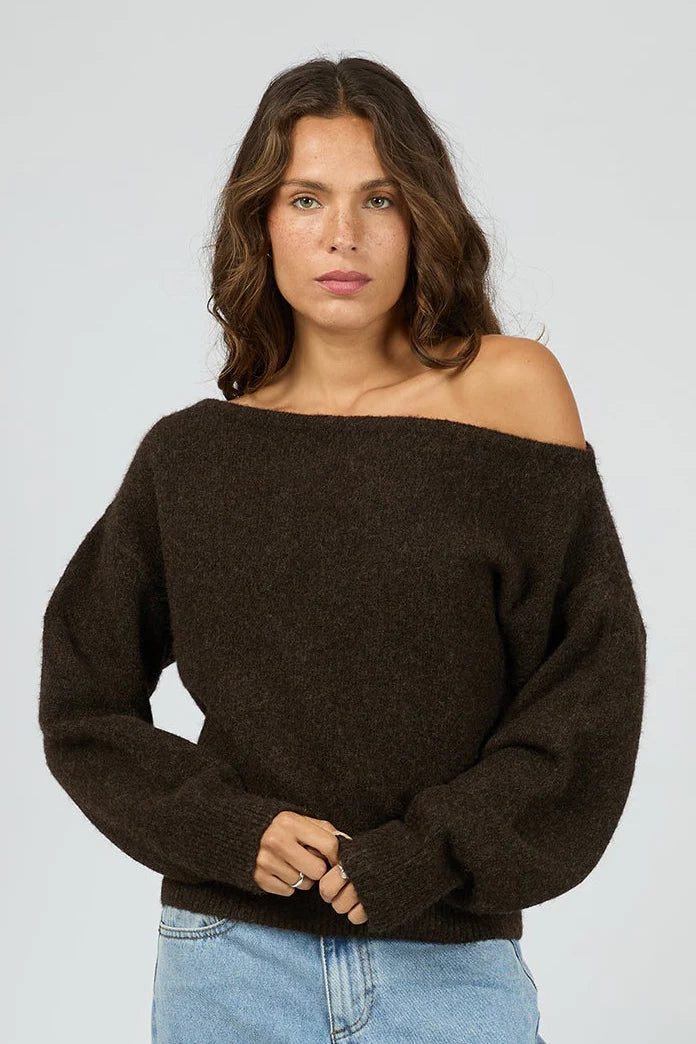 Woman wearing a dark brown off-shoulder sweater against a light gray background