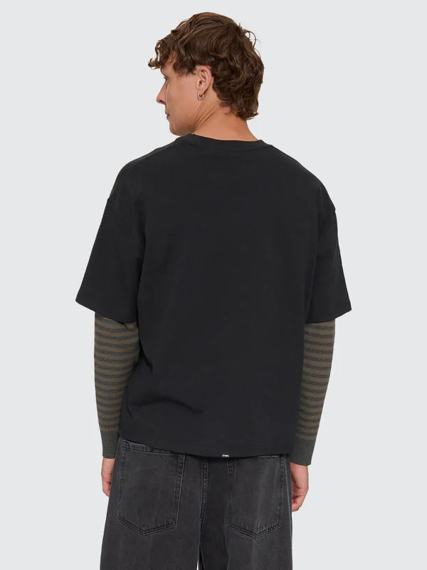 Person wearing a black t-shirt with green sleeves on a white background